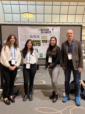 Professor Andreas Wilke poses with 3 students in front of their poster