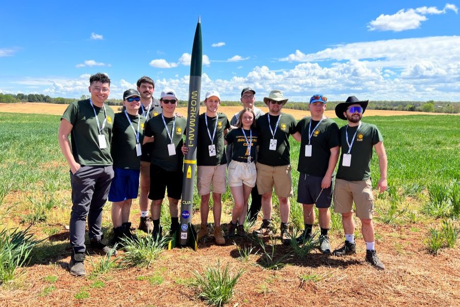 A photo of the rocketry club in a field with one of their projects.