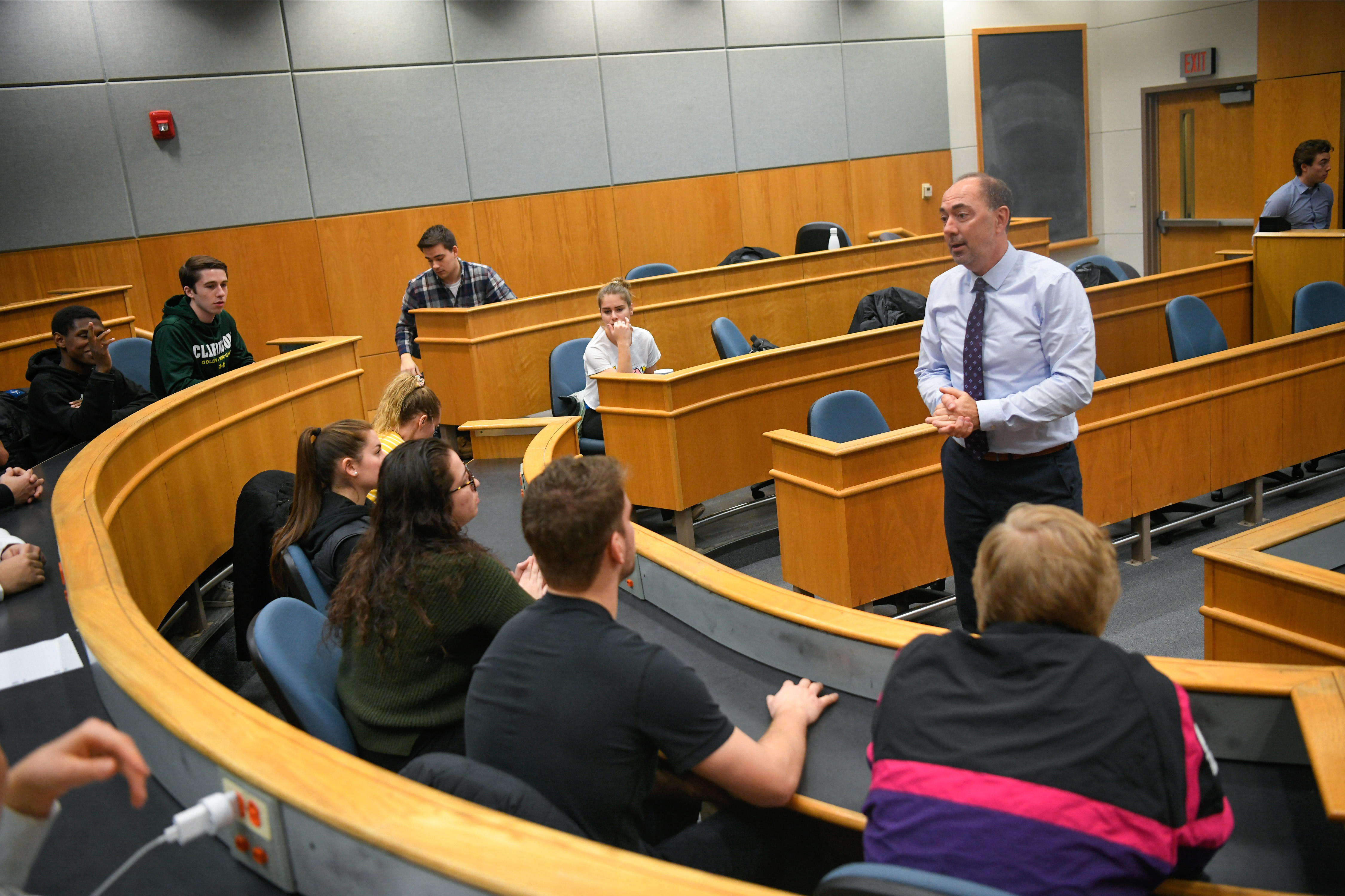 A professor stands in front of students while giving a lecture