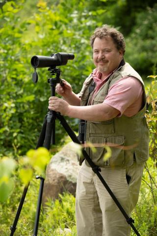 Environmental portrait of Professor Tom Langen using a spotting scope.