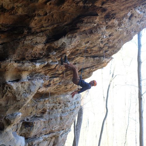 A photo of Blake Bundesmann hanging mid air while climbing.