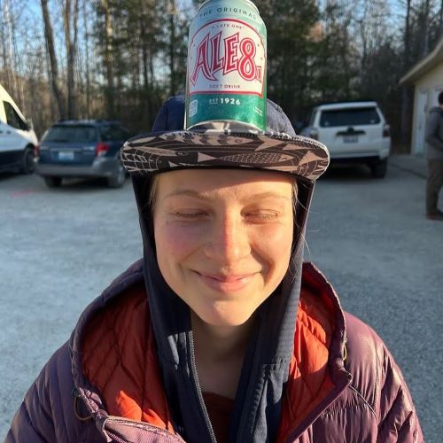 A photo of Lauren Marci smiling with a soft drink balancing on her head.