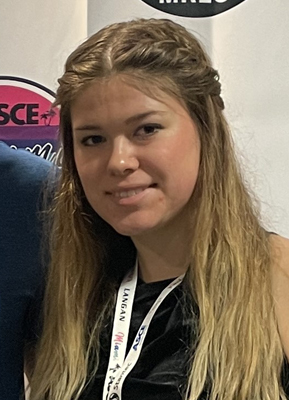 Shoulders up portrait of Kylie Nowicki in black shirt with white lanyard around neck