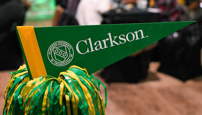 Green and gold pennant with word "Clarkson" and University seal positioned atop a green and gold pom pom