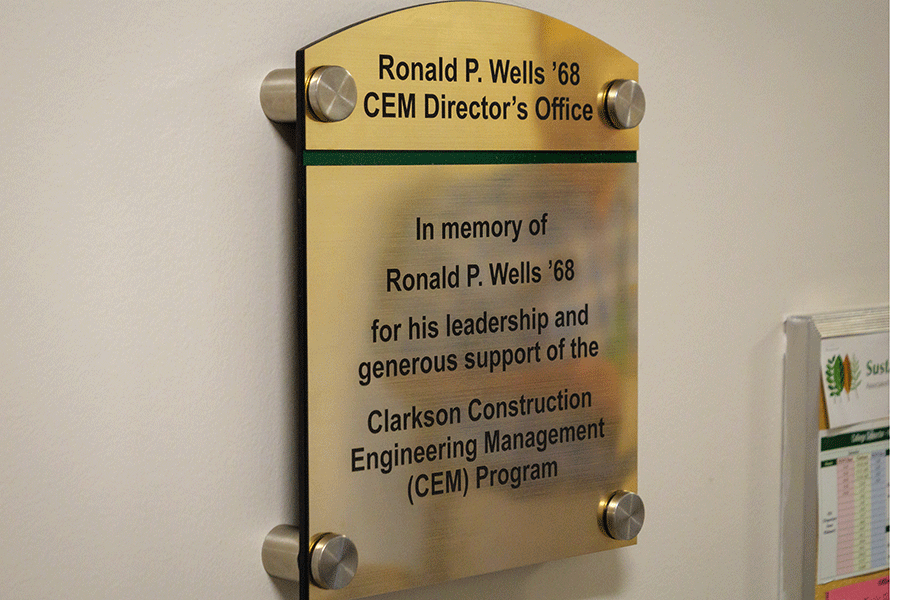 A plaque hands on a wall honoring the late Ronald P. Wells '68.