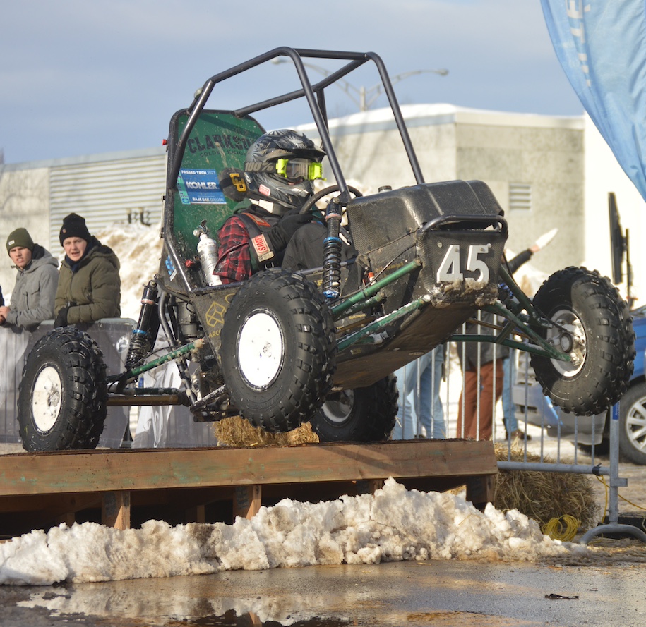 Baja SAE car over a jump with snow on the ground