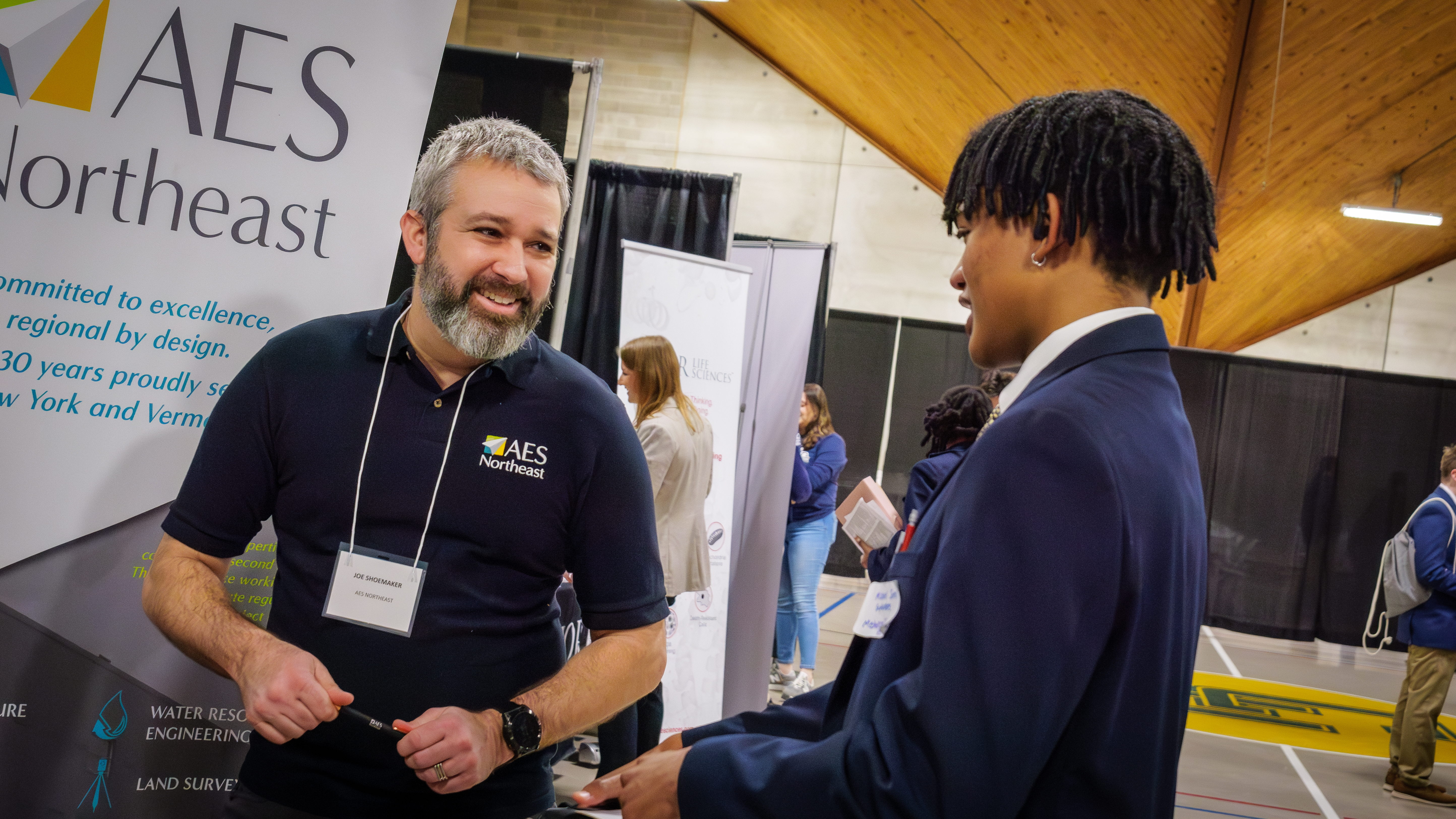 A company representative speaks with a student during a career fair event. 