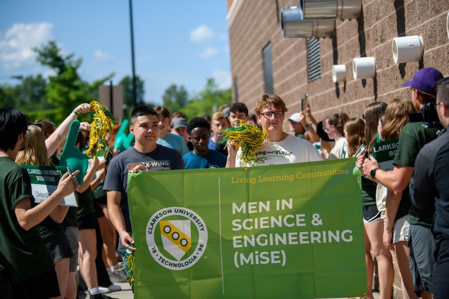 A photo of the 2024 Men in science and engineering living learning community holding a banner