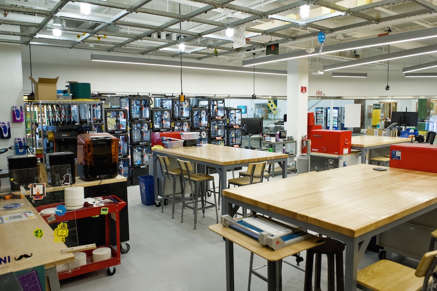 A room filled with 3D printers, large tables, hand tools, and other physical creation equipment.