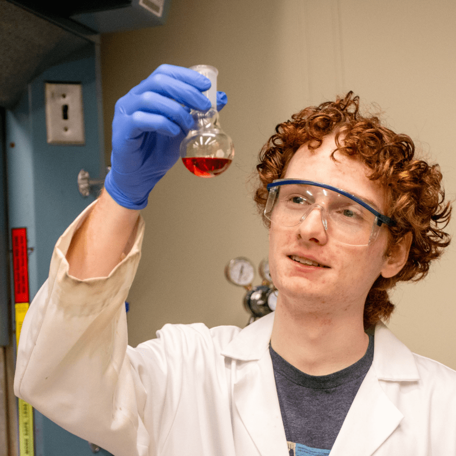 Matthias Schmidt in a lab coat holding a glass container with red fluid