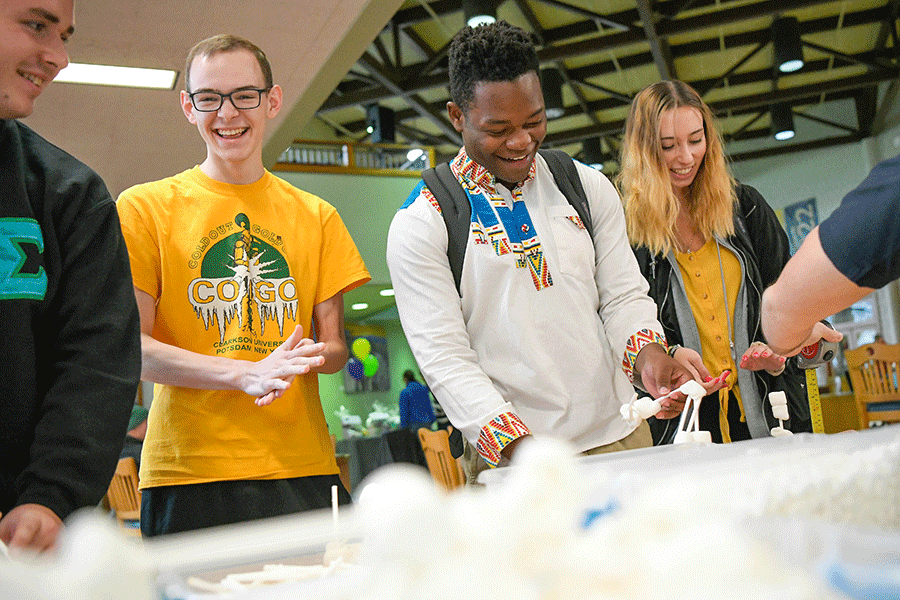 Students stand at a table and make houses out of sticks and marshmallows as part of a Clarkson Ignite event in the Educational Resources Center.