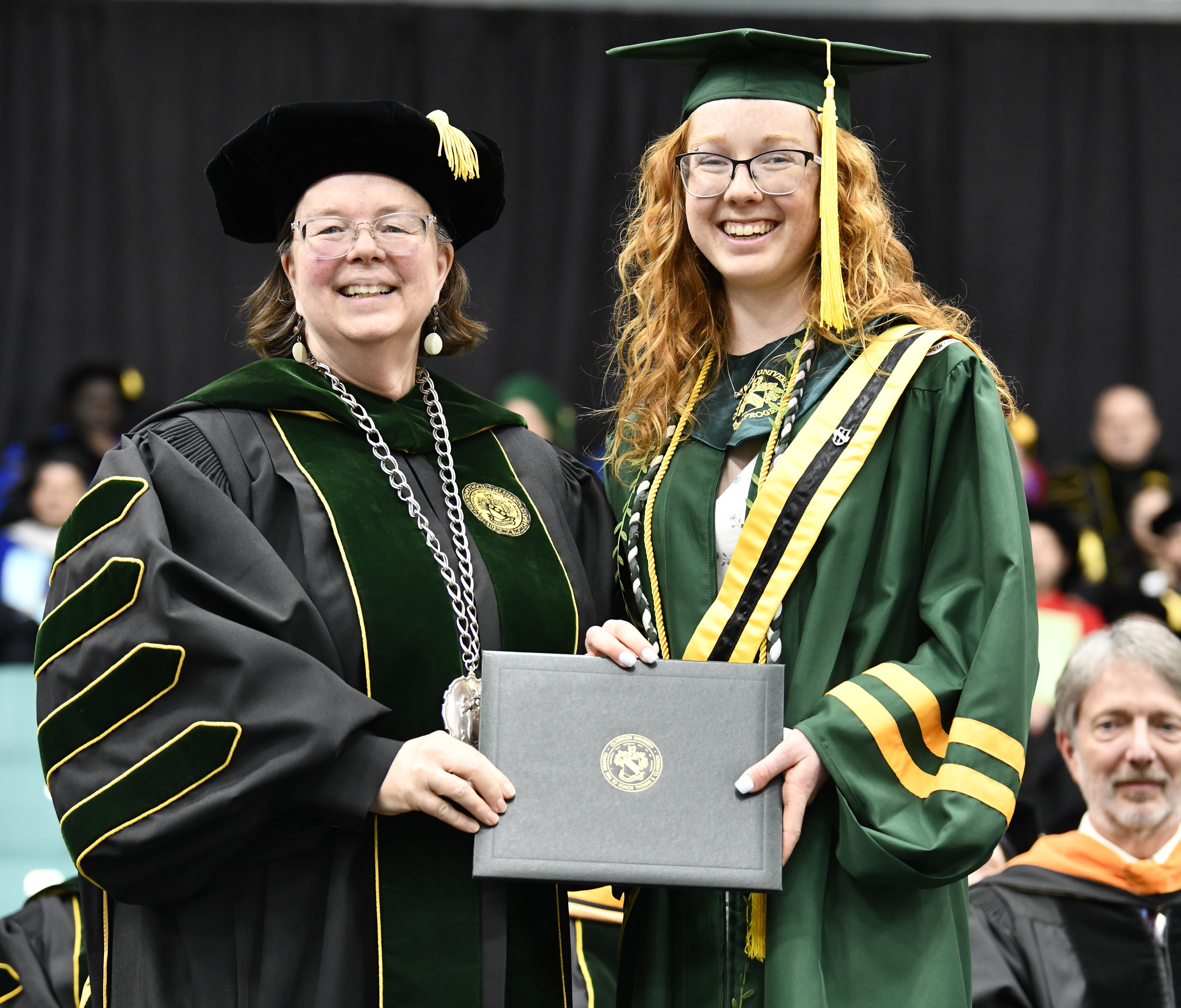 A university president presents a degree to a graduating student