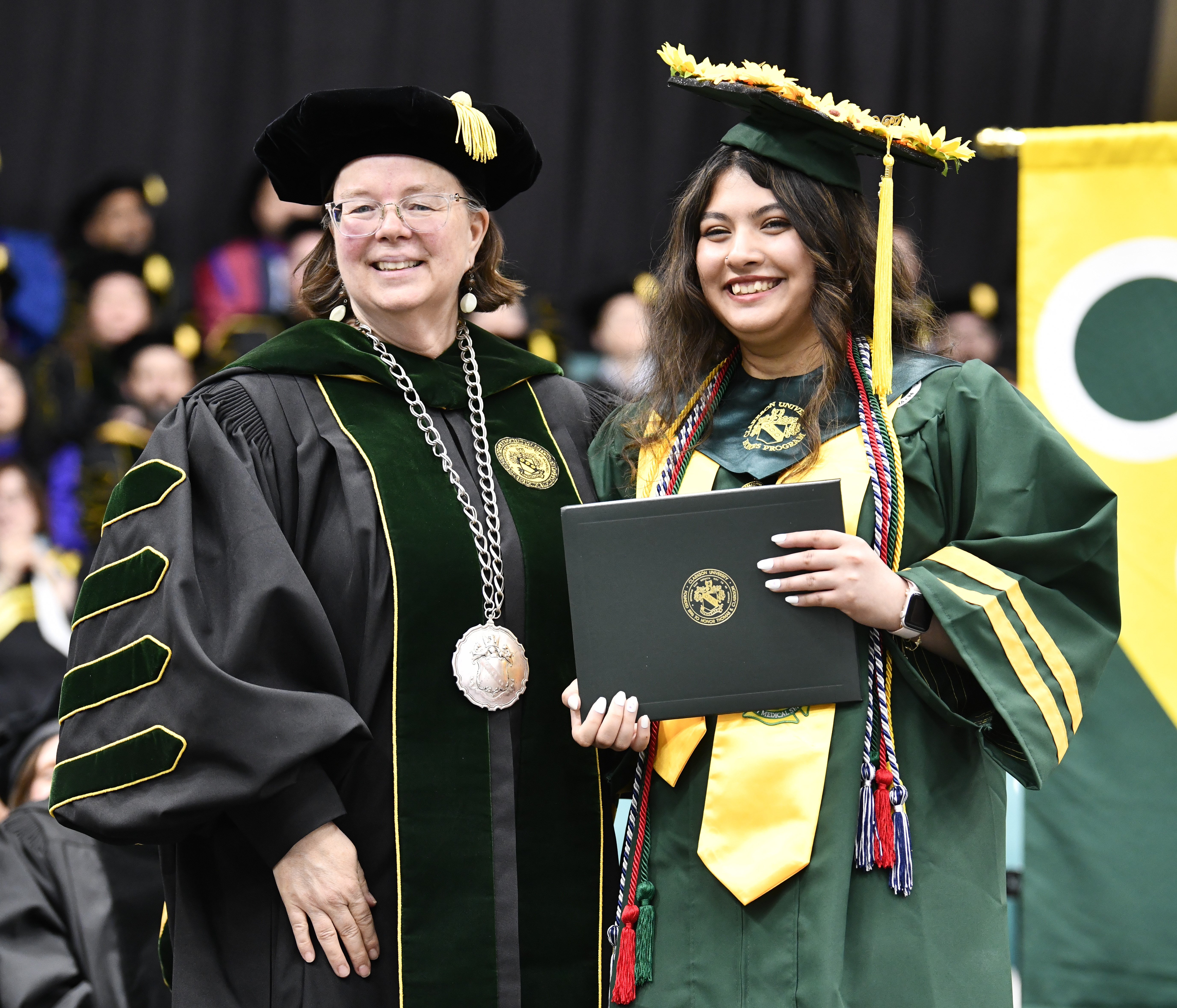 A university president presents a degree to a graduating student