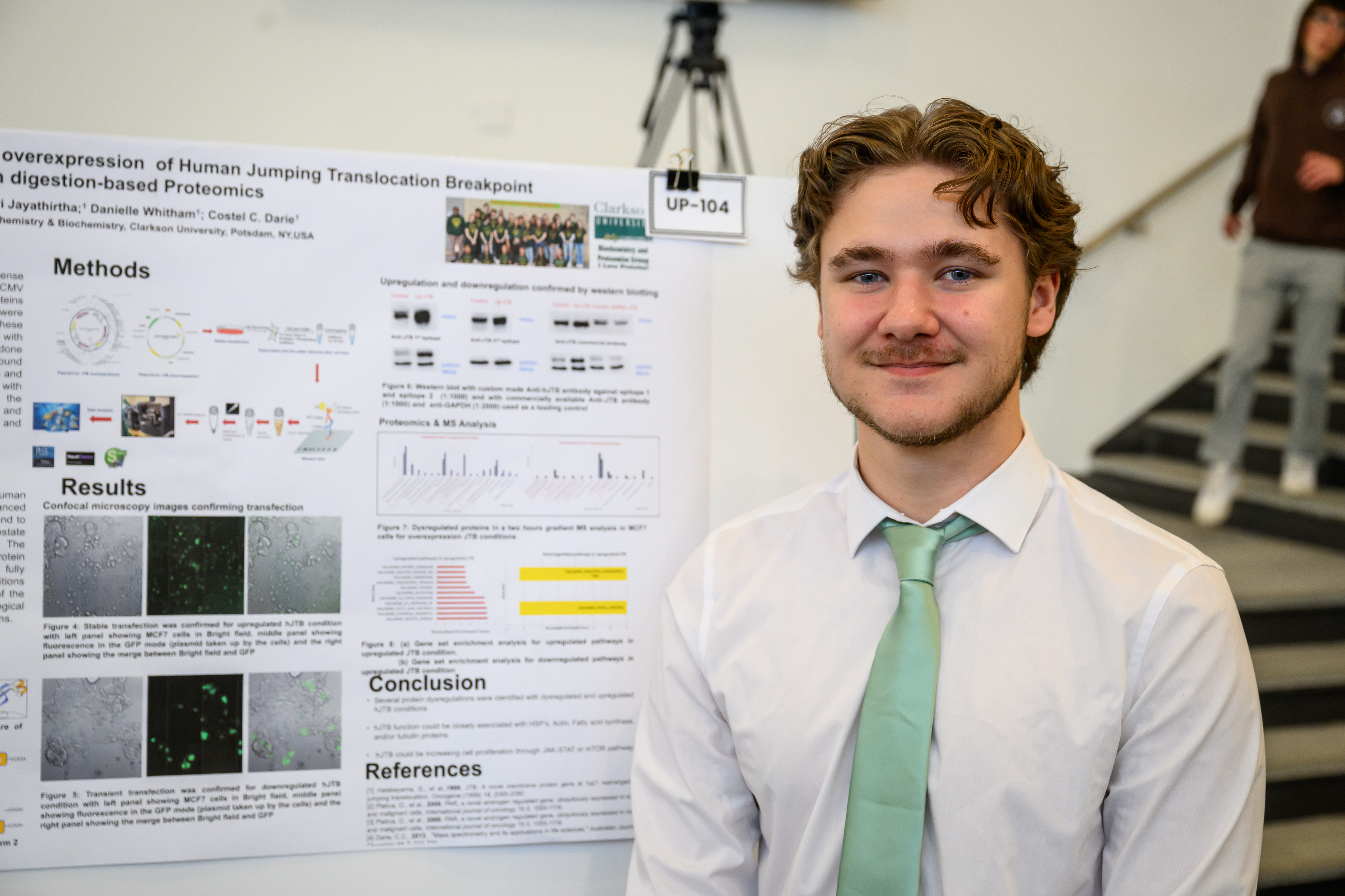A photo of a student posing with his Prometrics research poster.