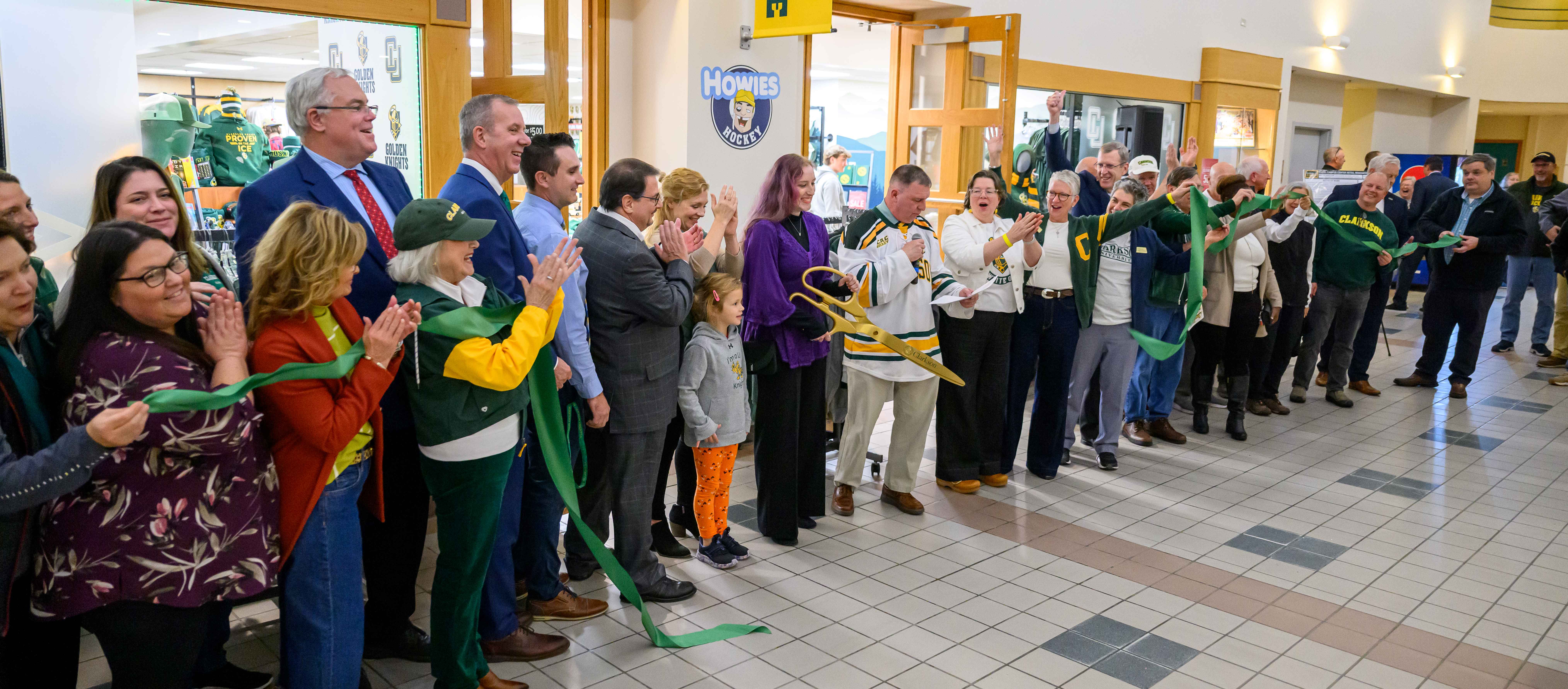 Dozens of people stand in celebration in front of Clarkson's book store as they hold the ribbon just after it was cut.