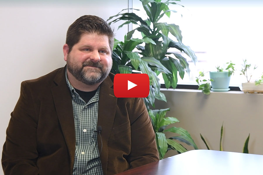 Clarkson alum and instructor John Meyer looks at the camera and there is a red play button on the image